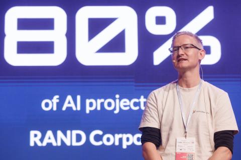 Image of Phil Winder at ITAPA in Bratislava with a headline of “80% of AI projects fail” behind him.