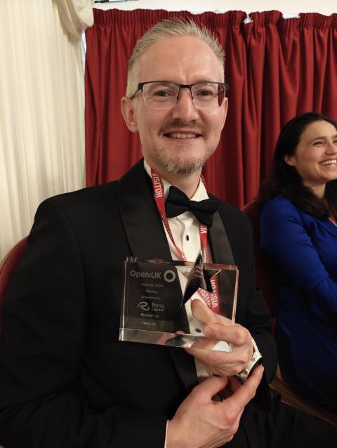 Phil Winder in black tie holding the OpenUK Awards 2024 Startup runner-up trophy, engraved for Helix ML